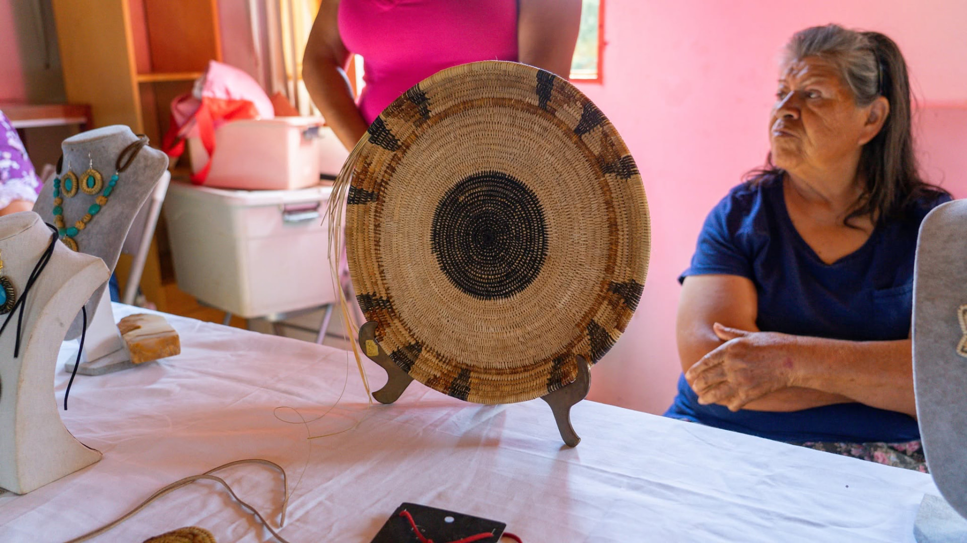 Artesana kumiai junto a un sawil de junco tejido